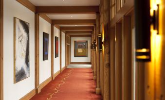 a long , well - lit hallway with wooden walls and red carpet , decorated with paintings on the walls at CordeValle