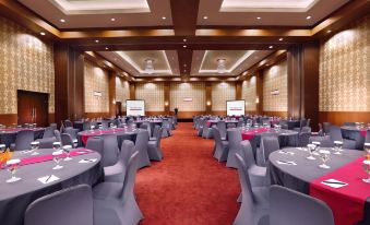 a large conference room with rows of tables and chairs , a podium , and two screens at favehotel Rembang