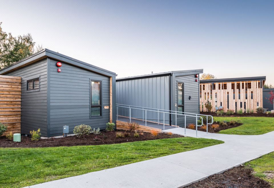 a modern , gray building with white trim and large windows , surrounded by green grass and trees at Lodges on Vashon