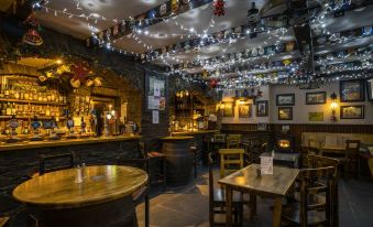 a cozy pub with wooden tables , chairs , and a bar area adorned with string lights at The Forth Inn