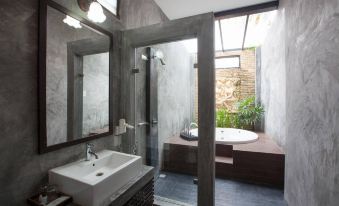 a modern bathroom with a large bathtub and a glass shower enclosure , surrounded by gray walls at Chalicha Resort
