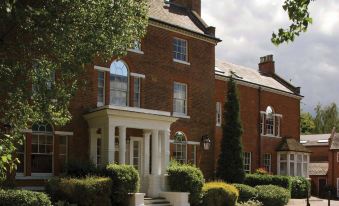 a large , red brick house surrounded by trees and bushes , with a driveway leading up to the front door at Best Western Moore Place Hotel