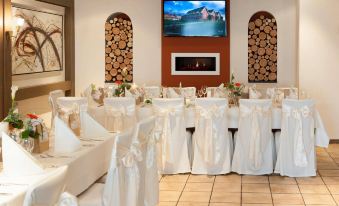 a large banquet hall with multiple tables covered in white tablecloths and chairs arranged around them at Hotel Hirsch
