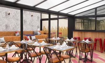 a restaurant with wooden tables and chairs , a pink rug , and large windows overlooking the city at Hotel Izzy