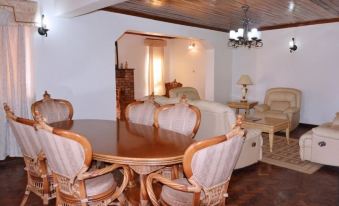 a dining room with a round wooden table surrounded by chairs , and a couch in the background at White Horse Inn