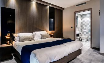 a large bed with white and blue bedding is in a room with wooden walls and a glass door at The District Hotel