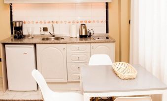a small kitchen with a dining table and chairs , as well as a refrigerator and microwave at La Palmera Rooms