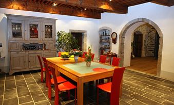 a dining room with a wooden table and chairs , along with a kitchen in the background at Le Manoir