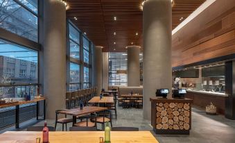 a modern restaurant with wooden tables and chairs , a bar , and large windows in the background at Hyatt Regency Seattle