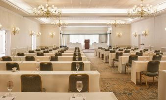 a large conference room with rows of tables and chairs , a glass of water , and chandeliers at The Equinox