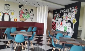 a restaurant with blue tables and chairs , a black and white checkered floor , and a mural on the wall at Citihub Hotel @Kediri