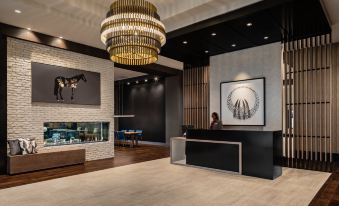 a modern lobby with a reception desk , a large chandelier hanging from the ceiling , and a painting on the wall at Crowne Plaza North Augusta