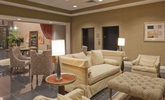 a well - lit living room with various pieces of furniture , including a couch , chairs , and a dining table at Holiday Inn Carbondale-Conference Center