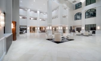 a large , white hotel lobby with multiple chairs and couches arranged in a seating area at Holiday Inn Wilmington