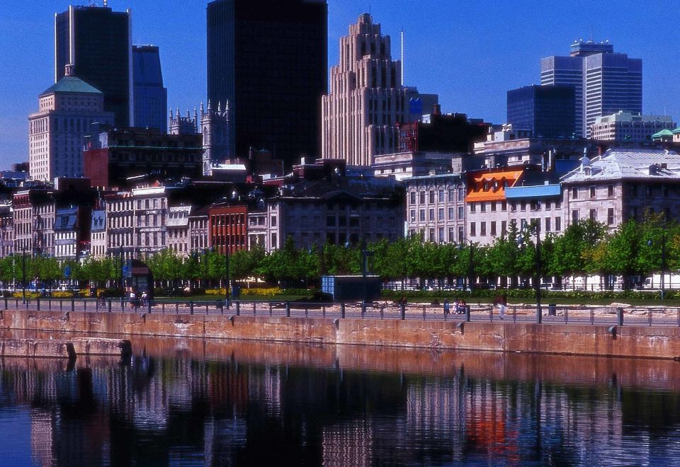 a city skyline with buildings , including skyscrapers , and a body of water in the foreground at Novotel Montreal Center