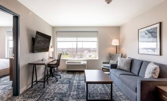a modern living room with a couch , coffee table , and tv . also a dining table in the room at Four Points by Sheraton Elkhart