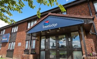"a blue building with a sign that reads "" travelodge "" prominently displayed on the front of the building" at Travelodge Peterborough Alwalton
