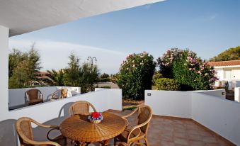 a patio with a table and chairs , surrounded by potted plants and overlooking the ocean at La Plage Resort