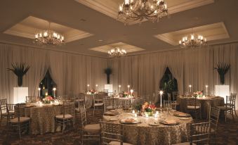 a well - lit banquet hall with multiple round tables and chairs set up for a formal event at Four Seasons Resort Nevis
