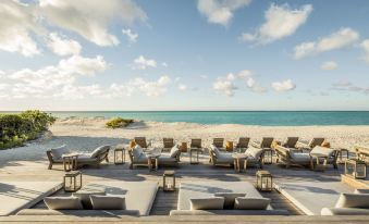 a beautiful beach scene with a group of people sitting on lounge chairs and a view of the ocean at Como Parrot Cay