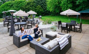 a man and a woman are sitting on a patio , enjoying each other 's company while enjoying a cup of coffee at Aubrey Park Hotel