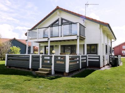 a large , two - story house with a wrap - around porch and white siding , surrounded by green grass and trees at Moon Face