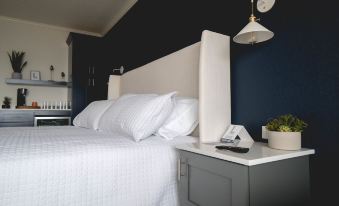 a bed with white sheets and pillows is next to a nightstand in a bedroom at Lakeside Inn