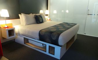 a large bed with a white headboard and footboard , topped with a black and white comforter at Room Motels Gympie
