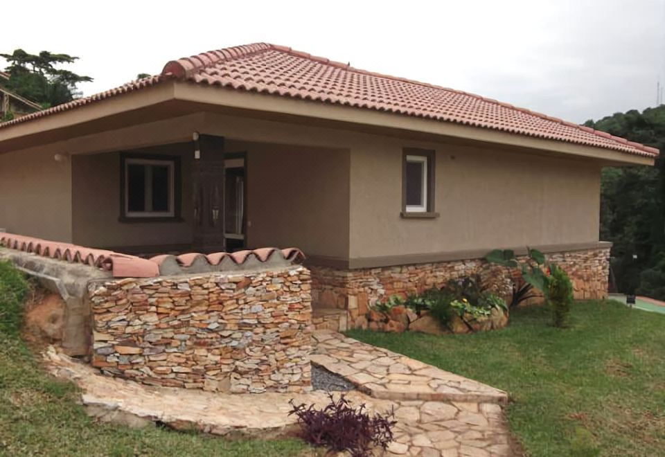 a house with a red tile roof and stone wall has a small entrance and steps leading up to it at The Lansdown