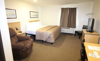 a hotel room with a bed , couch , and other furniture , including curtains and a bed at Amelia Extended Stay & Hotel
