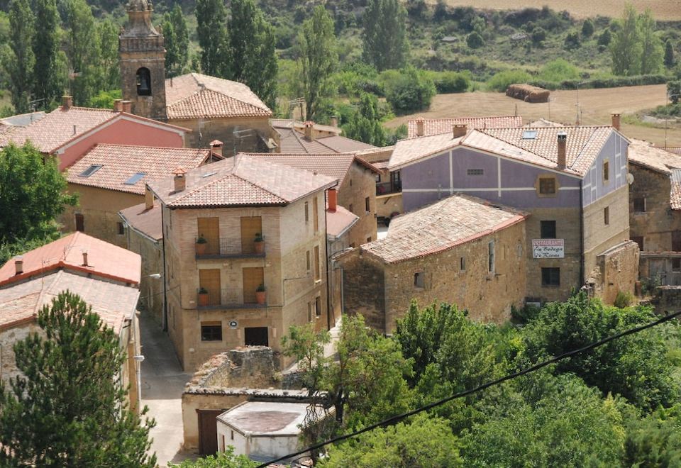 an old village with a mix of stone and wooden buildings , surrounded by greenery and a small church at La Casa de Alberto