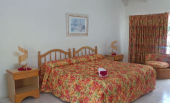 a large bed with a floral patterned comforter is in the middle of a room with wooden headboards at Anchorage Inn