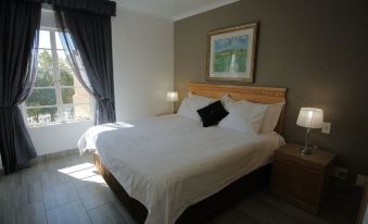 a large bed with white sheets and a wooden headboard is in a room with a window at Airport Inn and Suites