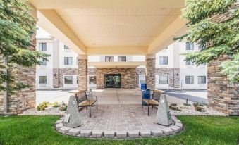 a modern hotel entrance with stone pillars , greenery , and a paved patio , providing a welcoming atmosphere for guests at Comfort Inn & Suites North Aurora - Naperville