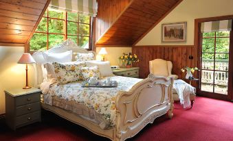 a cozy bedroom with a large bed , red carpet , and a view of the mountains outside the window at Mary Cards Coach House