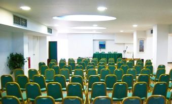 a conference room with rows of chairs arranged in a semicircle , and a podium at the front of the room at Erofili Beach Hotel