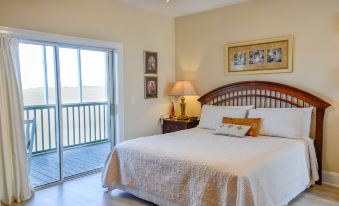 a spacious bedroom with a king - sized bed and a door leading to a balcony overlooking the ocean at The Sunset Inn