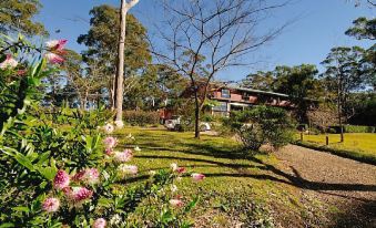 a garden with a variety of flowers , including pink and white ones , in front of a house at Bilpin Country Lodge