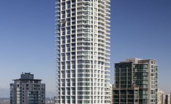 a tall white building with many windows is surrounded by other buildings in a city at Element Vancouver Metrotown