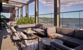 an outdoor seating area on a rooftop with couches , chairs , and a view of the water at Radisson Blu Caledonien Hotel, Kristiansand