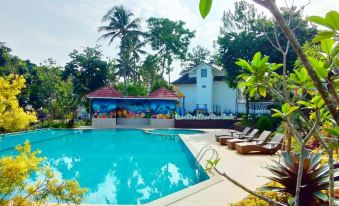 a beautiful swimming pool with sun loungers , umbrellas , and trees surrounding a white building under a blue sky at Chevilly Resort & Camp