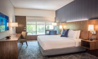 a modern hotel room with a large bed , white bedding , and a balcony view , accompanied by comfortable seating and desk at Inn at Villanova University