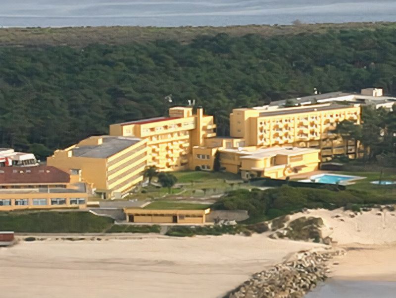 a large hotel complex surrounded by trees and a beach , with the ocean visible in the background at Axis Ofir Beach Resort Hotel