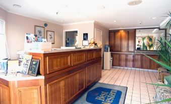 "a reception area of a hotel with a wooden counter and a blue rug with the word "" best western "" written on it" at Best Western Plus Executive Suites