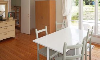 a white dining table with chairs in a room with hardwood floors and a window at Simrishamn