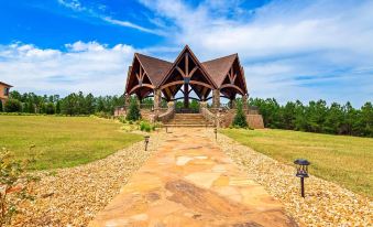 a wooden structure with a triangular roof is surrounded by rocks and trees , leading to a stone pathway at Aiden by Best Western @ Warm Springs Hotel and Event Center