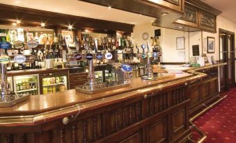 a bar with a long wooden counter and various bottles and glasses on the counter at Burnley West Higher Trapp Hotel