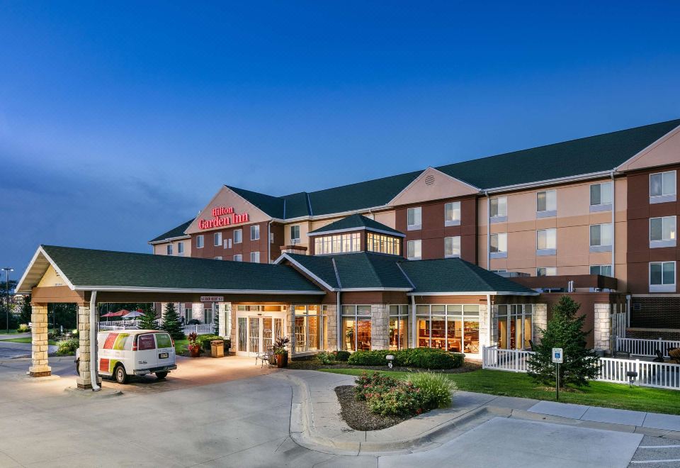 an exterior view of a large hotel , possibly a hotel or an inn , with a parking lot in front at Hilton Garden Inn Omaha West