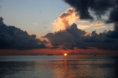 a beautiful sunset over the ocean , with a silhouette of a boat in the distance at Vilamendhoo Island Resort & Spa