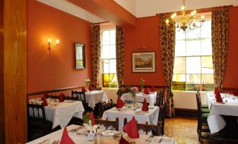 a well - decorated dining room with multiple tables and chairs , all set for a meal or a party at Londonderry Arms Hotel